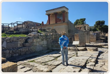 Visitor gazing at the ancient ruins and restored frescoed building of Knossos Palace in Crete