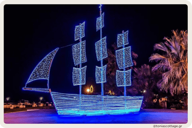 Large ship-shaped holiday light display glowing blue at night, during Christmas in Crete.