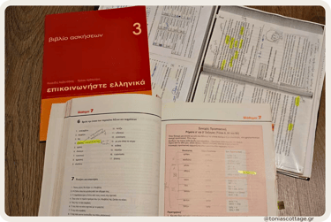 Greek language exercise books and study notes laid out on a table