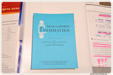 Greek language exercise books and study notes laid out on a table