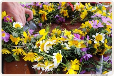 Hands weaving a colourful wildflower wreath for May Day in Crete.