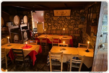 Candlelit interior of Giannis' Tavern with stone walls and wine barrels in Kyparissos, Crete.