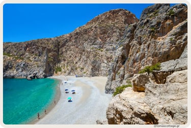 Agiofarrago Gorge in Crete, with high rocky walls, some trees, and a quiet beach meeting the sea