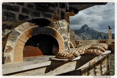 Loaves of bread cooling by a stone oven, with Asterousia mountains in the background.