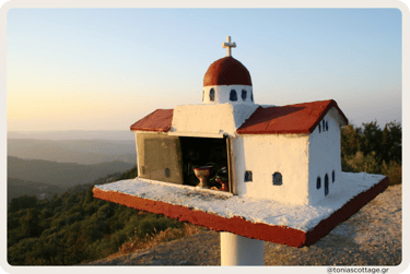 A roadside shrine with a red roof in Crete, illuminated by the sunset glow
