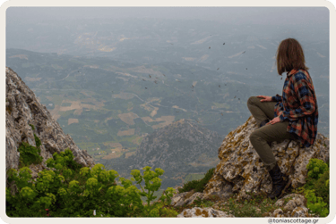 Woman sitting with a view of the valley in the mountains of Crete, surrounded by nature