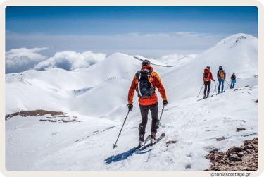 kiers on snow-covered mountains in Crete with clear skies and sunny weather