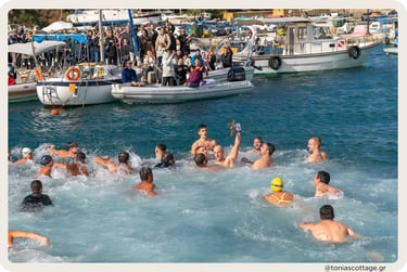 Swimmers in the sea during Epiphany, with people watching from boats in the harbor of Crete