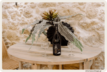 Table at Tonia's Cottage with a bottle of Lyrarakis wine and two glasses, set for a relaxing moment