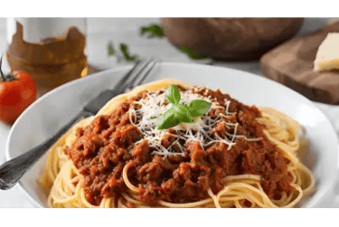 Μακαρονάδα με κιμά και βασιλικό σε λευκό πιάτο