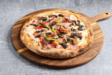 Freshly baked homemade pizza with mushrooms, ham, and peppers on a wooden serving board.