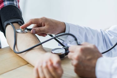 A doctor uses a stethoscope and manual cuff to check a patient's blood pressure during a medical exam.