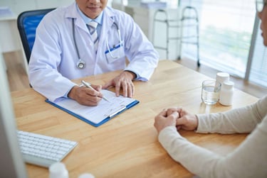 A doctor in a white coat consulting with a patient and writing medical notes on a clipboard.
