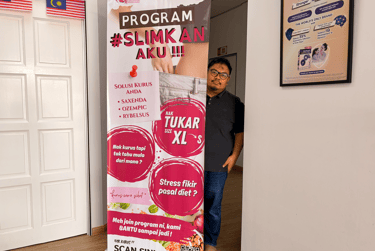 A man stands behind a clinic banner advertising weight loss programs and Ozempic treatments.