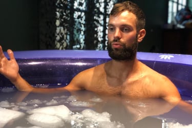 Bearded man sits in a portable ice bath tub for cold water immersion recovery.