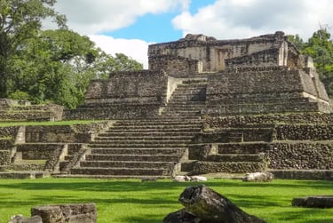 Ancient Mayan ruins of Caracol in Belize featuring a stone pyramid temple with stairs.