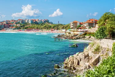 Panoramic view of the Black Sea coastline in Sozopol, Bulgaria, featuring a rocky shore and sandy beach.