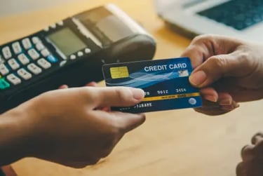 Customer hands over a blue credit card to a cashier near a POS terminal for a retail payment.