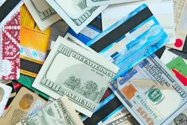 A scattered pile of US hundred dollar bills and multiple credit cards representing personal finance and debt.