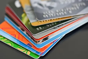 A fanned-out stack of colorful credit cards and debit cards on a dark reflective surface.