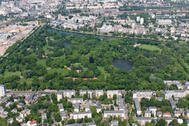 Aerial view of Skaryszewski Park in Warsaw featuring lush green trees, lakes, and surrounding city buildings.