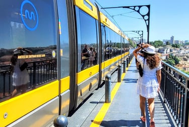 Lili walking along the Dom Luís I Bridge as a train passes by on a sunny day in Porto.