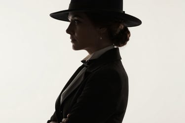 Silhouette profile of a woman in a black fedora hat and vintage blazer with arms crossed.