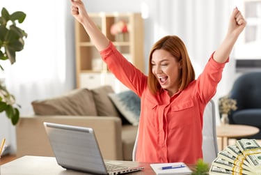 a woman with happy while looking to her laptop with lot of money on the table for boosting sales