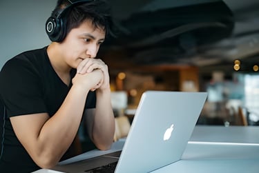 Student focusing on SAT prep with laptop and headphones, highlighting Admit 360's online SAT test