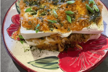 a plate with a slice of tofu and enoki mushrooms on it