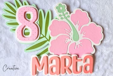 Big pink tropical  flower and leaf with number 8 on it. Name Marta sitting next to them. All made wi
