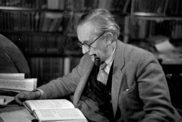 Tolkien fumant la pipe et lisant à son bureau