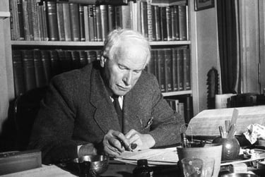 A black and white potrait of Swiss psychatrist Carl Jung sitting in his office writing something.