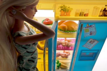 a barbie doll standing in front of a refrigerator