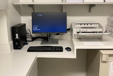 A desktop computer workstation with a Dell PC, monitor, and high-speed document scanner on a white office desk.