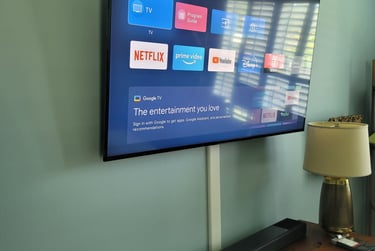 A wall-mounted smart TV with a cable concealer kit above a soundbar and dresser.