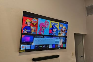 A wall-mounted LG smart TV displaying a children's streaming menu with a black soundbar underneath.
