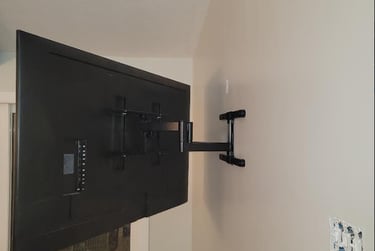 Full motion articulating TV wall mount bracket extending a flat screen television from a wall.
