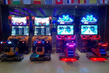 A row of neon lit arcade motorcycle and SnoCross racing games under international flags.