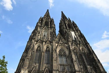 Low-angle view of the Gothic twin spires of the Cologne Cathedral against a blue sky in Germany.