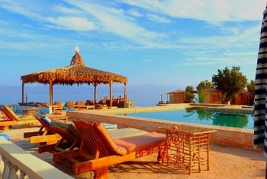 una piscina de campamento en la playa con tumbonas y sombrillas