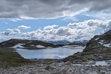 a mountain lake with puffy clouds in a blue sky