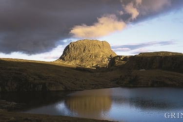 a lake in the foreground with a rock formation on the horizon
