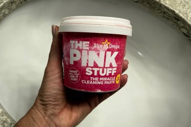 Hand holding The Pink Stuff Miracle All Purpose Cleaning Paste over a bathroom sink