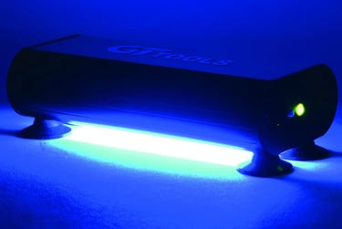 GT Tools UV curing light for windshield repair emitting a bright blue glow on a flat surface.