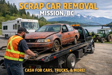 Tow truck loading rusty scrap car near Mission Bridge with mountains behind.