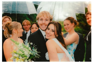 Bride and groom celebrating with their bridal party under clear umbrellas