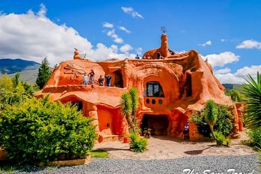 Exterior view of the giant clay Terracotta House with visitors walking on its terraces under a blue sky