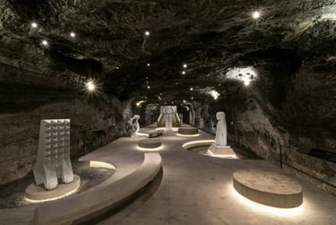 Modern white stone sculptures displayed inside the illuminated underground museum of Zipaquira salt mine.