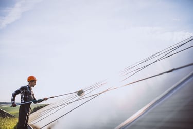 Agent qui nettoie un panneau solaire à la perche